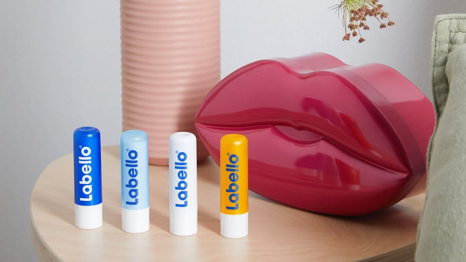 Vier Labello Lippenpflegestifte arrangiert auf einem Beistelltisch
